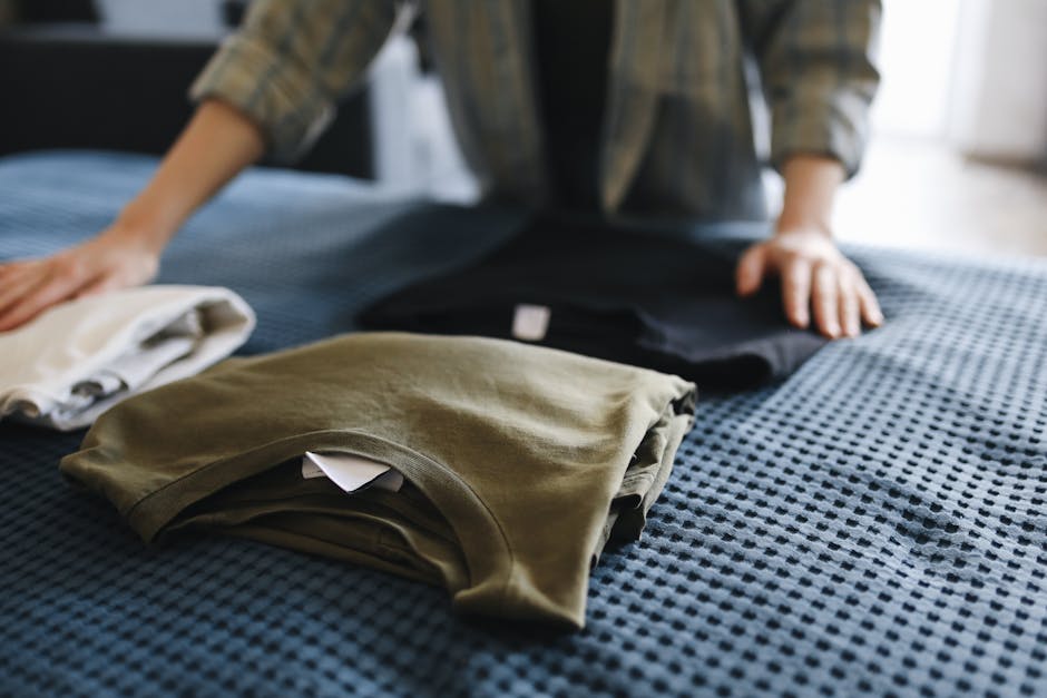 close up of hands organizing neatly folded clothes in drawer