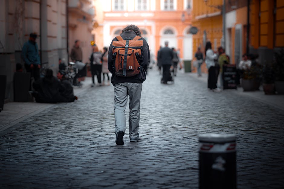 person with backpack walking on cobblestone street