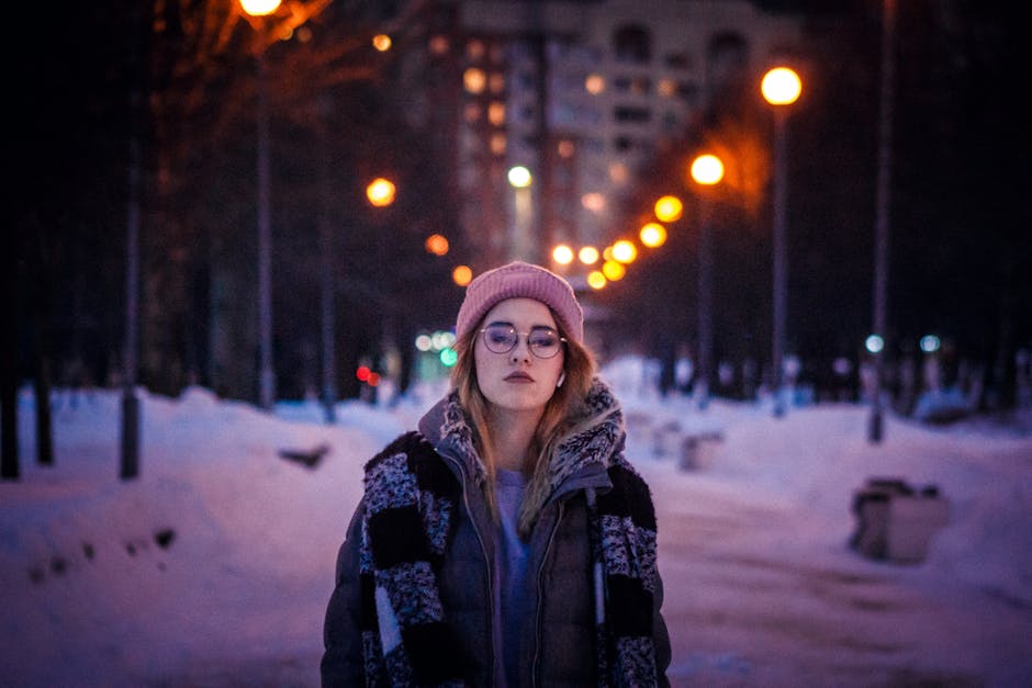 woman in warm winter jacket and hat in snowy city